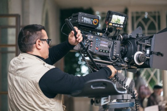 Camera operator with modern professional equipment working during film shooting